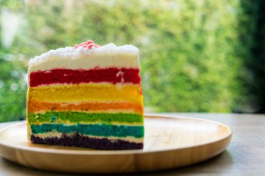 Gökkuşağı kek doğa yeşil bokeh ba ile ahşap bir plaka üzerine yerleştirilir