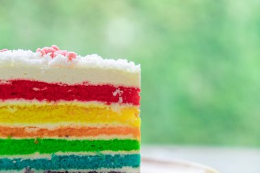 Gökkuşağı kek doğa yeşil bokeh ba ile ahşap bir plaka üzerine yerleştirilir