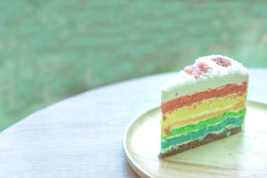 Gökkuşağı kek doğa yeşil bokeh ba ile ahşap bir plaka üzerine yerleştirilir