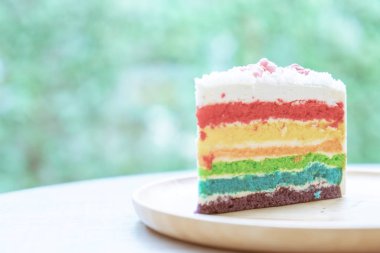 Gökkuşağı kek doğa yeşil bokeh ba ile ahşap bir plaka üzerine yerleştirilir