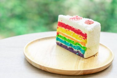 Gökkuşağı kek doğa yeşil bokeh ba ile ahşap bir plaka üzerine yerleştirilir