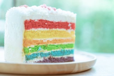 Gökkuşağı kek doğa yeşil bokeh ba ile ahşap bir plaka üzerine yerleştirilir