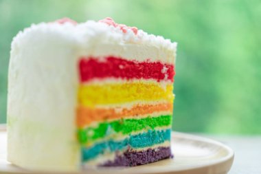 Gökkuşağı kek doğa yeşil bokeh ba ile ahşap bir plaka üzerine yerleştirilir