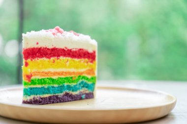 Gökkuşağı kek doğa yeşil bokeh ba ile ahşap bir plaka üzerine yerleştirilir