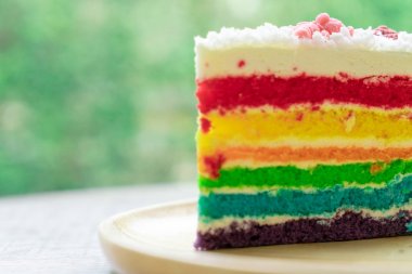 Gökkuşağı kek doğa yeşil bokeh ba ile ahşap bir plaka üzerine yerleştirilir