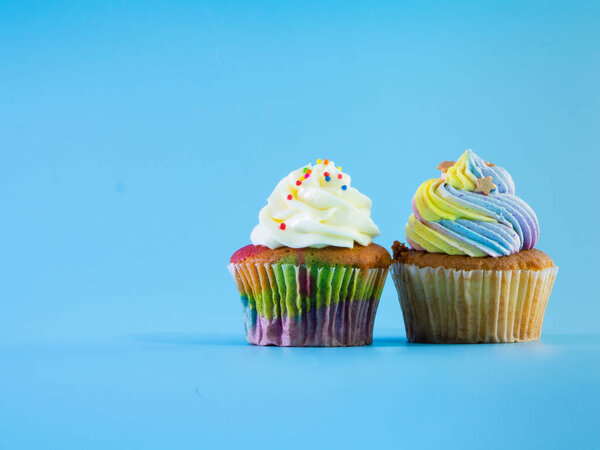 Colorful and enteresting cupcake isolated on blue background studio close up shot.