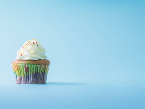 Colorful and enteresting cupcake isolated on blue background studio close up shot.