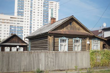 Şehir manzarası. Yeni binaların arka planında geleneksel Rus kulübesi. Kahverengi mavi-beyaz arka planda.