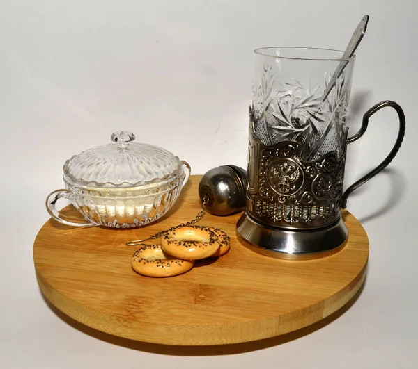 Russian tea, a glass in a silver cup holder, black tea, bagels with poppy seeds on a wooden tray