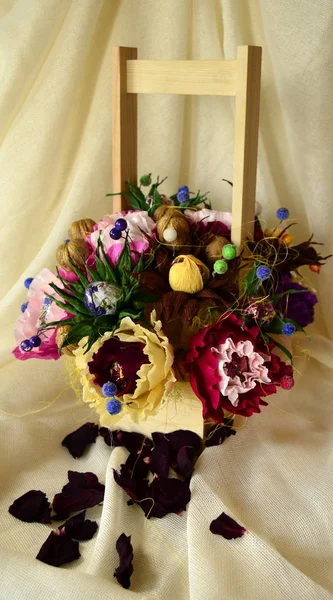 Artificial bouquet of candy and paper flowers: pink-red, blue, yellow flowers, walnuts