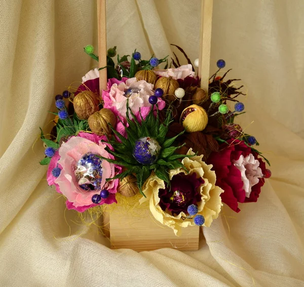 Artificial bouquet of candy and paper flowers: pink-red, blue, yellow flowers, walnuts