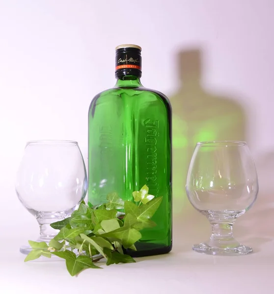 A bottle of green glass, two empty glasses, the shadow of a bottle. Creative side lighting