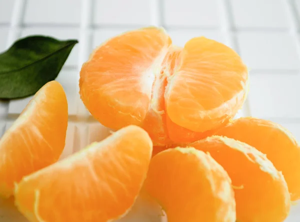 Slices of mandarin lie on a white heterogeneous surface. Tangerine slices close-up.