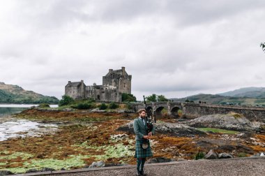 Dornie, İskoçya; 27 Ağustos 2019: Eilean Donan Kalesi'nin üzerinde müzik aletini çalan İskoç gaydacısı