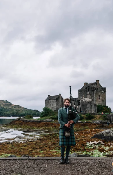 Dornie, İskoçya; 27 Ağustos 2019: Eilean Donan Kalesi'nin üzerinde müzik aletini çalan İskoç gaydacısı
