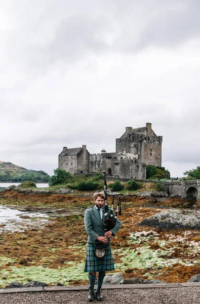 Dornie, İskoçya; 27 Ağustos 2019: Eilean Donan Kalesi'nin üzerinde müzik aletini çalan İskoç gaydacısı