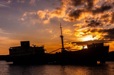 Deniz, gökyüzü ve gemi korozyon nedeniyle bazı delikler bulutlu gün batımı gösteren kısmında fotoğraflandı Lanzarote shore, batık siluet