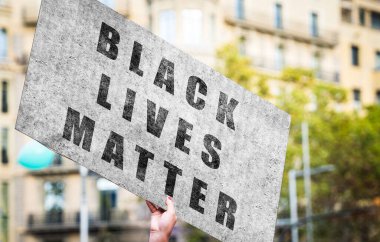 Siyahların hayatı önemlidir. Afrikalı Amerikalı protestocu elinde ırkçılık karşıtı güçlü bir mesajla bir poster tutuyor..