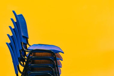 Mavi sandalyeler birbiri ardına turuncu arka planda. Okul ve akademi başkanlarının yeni normalliğe adaptasyonu.