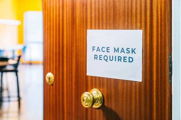 Okulun kapısında koruyucu bir tıbbi maske takmayı gerektiren bir tabela var. Böylece kovid19 yayılmaz. Okulların yeniden açılması ve yeni normallere uyarlanması.