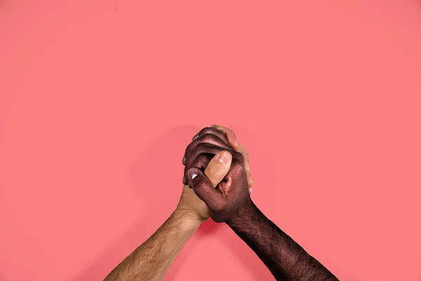 Multicultural hands united calling for freedom and equality on a red background. African black hand and caucasian white hand together calling for stop racism.