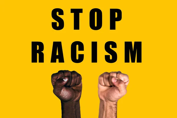 African black fist and caucasian white fist raised calling for freedom and equality on a yellow background. Multicultural fists raised. Stop racism.