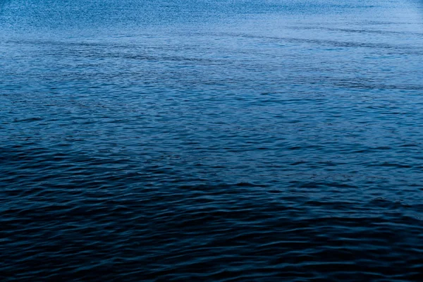 Background of a calm blue sea with the texture of the waves in the blue hour at sundown. Concept of climate crisis and refugee crisis in the Mediterranean Sea.