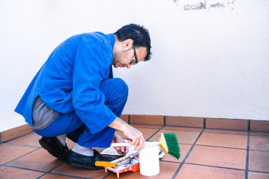 Olgun adam evin terasını boyamak için aletleri hazırlıyor. Evin köşelerini boyamak ve yeniden düzenlemek..