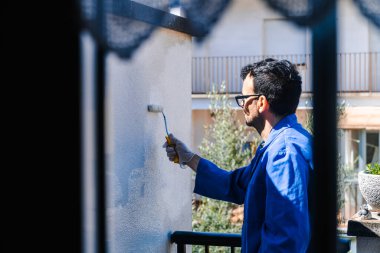 Terasın beyaz duvarını boyayan adam. Evin köşelerini boyama ve ıslah etme kavramı.