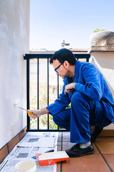 Man painting the white wall of the house terrace. Concept of painting and reforming the corners of the house.