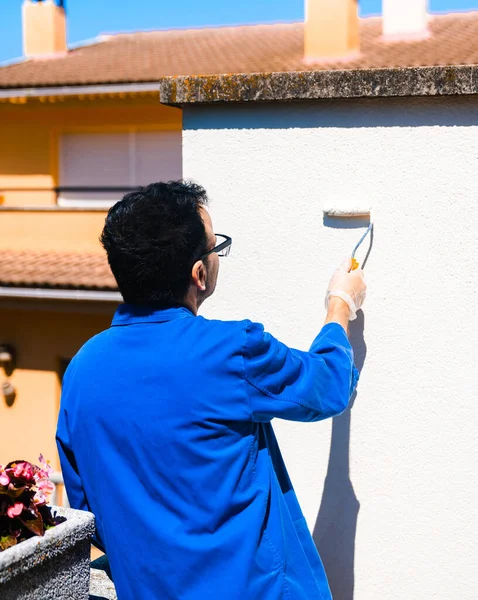 Man painting the white wall of the house terrace outside. Concept of painting and reforming the corners of the house.