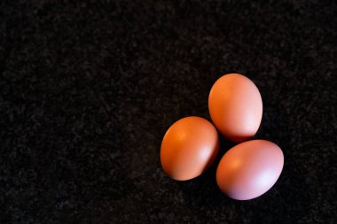 Ev yapımı kek yapmak için mutfak mermerinin üstüne üç yumurta koyun..