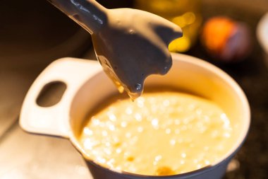 Yemek tarifi hazırlamak için kek hamurunu el blendırıyla karıştırmak. Evde ev yapımı bir pasta hazırla..