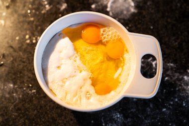 Yemek tarifi yapmak için un ve yumurta dolu beyaz alıcının üst görüntüsü. Evde ev yapımı kekin hazırlığı.