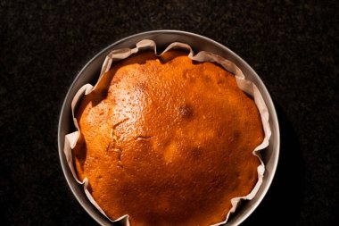 Sıcak mutfak ışığıyla fırından yeni çıkmış nefis bir ev yapımı pastanın üst görüntüsü. Mutfak mermerinin üstünde taze pişmiş sıcak kek..