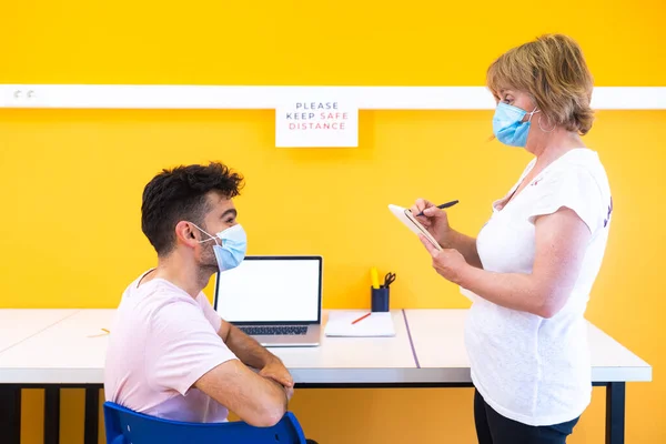 Teacher and student with a medical face masks at school. Doing class in the new normal during the coronavirus pandemic with the necessary preventive measures.