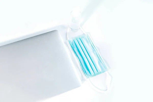 Moderner Laptop Mit Medizinischer Gesichtsmaske Und Händedesinfektionsflasche Auf Weißem Schreibtisch — Stockfoto