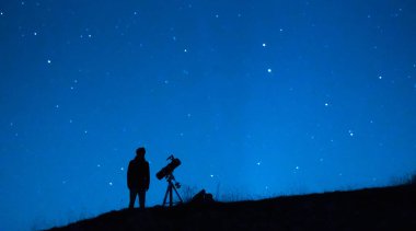 Astronom evrenin ve yıldızların büyüklüğünü gözlemliyor. Geceleri mavi yıldızlı gökyüzünü gözlemleyen teleskoplu bir astronomi aşığının silüeti..