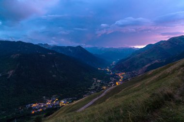 Gün batımında sokak lambalarının ışıklarıyla aydınlatılan küçük tipik dağ köyleri olan güzel bir vadi. Valle de Aran, Baqueira-Bere, Maaş, Lerida, Katalonya, İspanya 'nın panoramik manzarası.