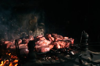 Evinin şöminesinde ızgara et. Mangal ızgarasında çiğ et ve altında kömür var..