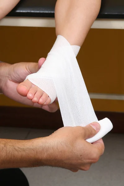 Doctor performing an ankle bandage on a girl