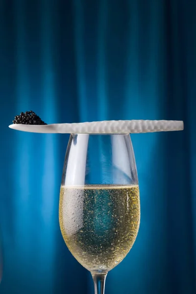 Widelec porcelanowe z kawioru i szampana, z niebieskim tłem — Zdjęcie stockowe