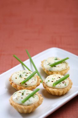 Mini peynir tartlets, kutlama için catering sunumu. Renkli masa örtüsü üzerinde servis edilir.