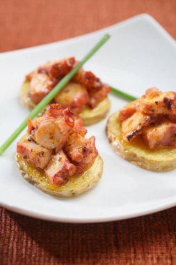 Ahtapot ile patates başlayanlar, kutlama için catering sunumu. Renkli masa örtüsü üzerinde servis edilir.