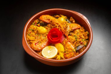 Koyu ahşap arka planda seramik kasede deniz ürünleri paella 'sı. Deniz mahsullü pilav.