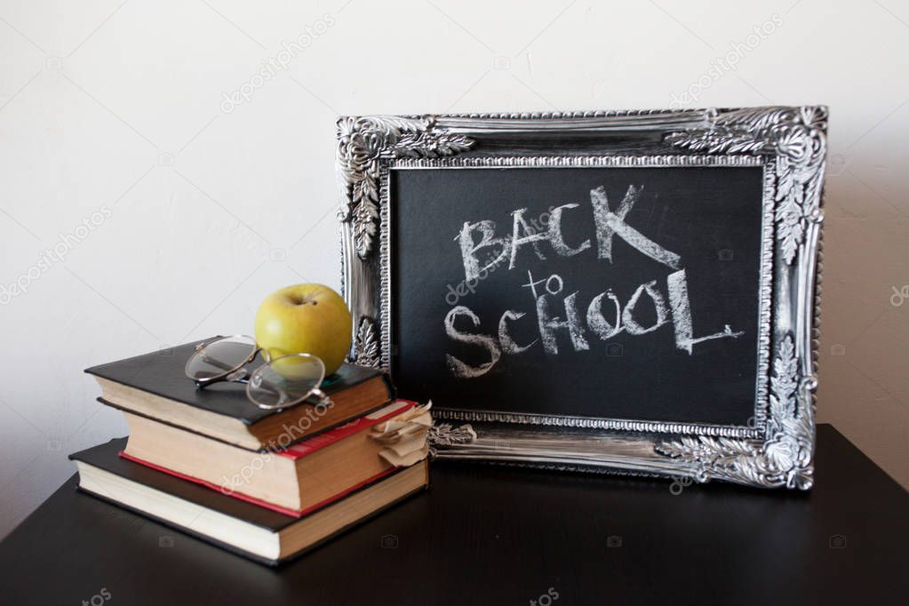 Back to school, chalk in a vintage frame. Text on chalkboard and a stack of textbooks