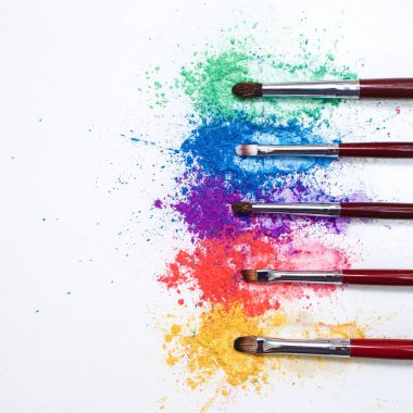 Beyaz bir arka planda Kozmetik için gökkuşağı ve fırçalar farklı renklerde parlak göz gölgeler.