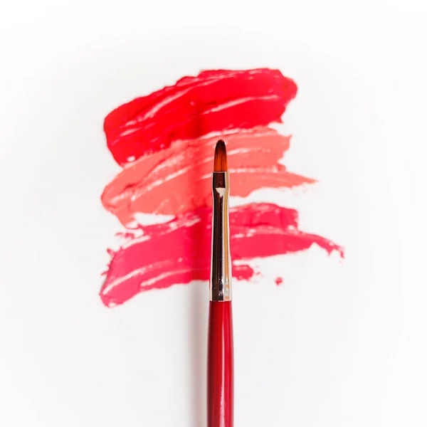 Lippenstift und Lipgloss, Tropfen und Striche in verschiedenen Schattierungen mit Pinseln zum Auftragen und Schattieren — Stockfoto