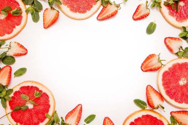 Schattige platte lag met vers fruit, gesneden aardbei en grapefruit of rood oranje, muntblaadjes op witte achtergrond. — Stockfoto