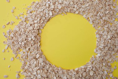 Sarı arka planda yulaf ezmesi taneleri, kopya alanı. Yulaf gevreği daire şeklinde yalan